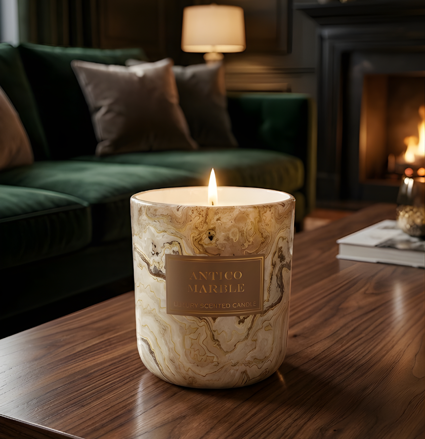 Brennende Luxus Duftkerze Antico Marble auf einem dunklen Holztisch im gemütlichen, eleganten Wohnzimmer-Ambiente mit Kaminfeuer und grünem Samtsofa – Best Bougie Premium Dekor
